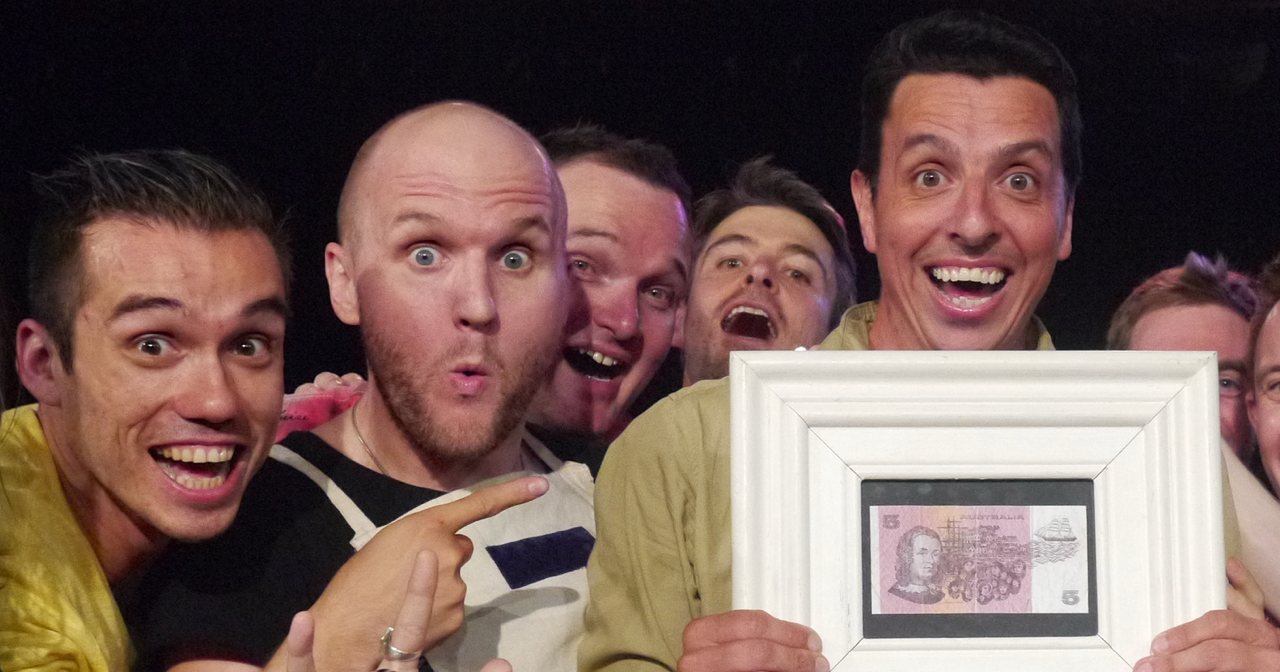 Rik Brown is surrounded by his fellow players as he hoists the Maestro™ framed $5 note