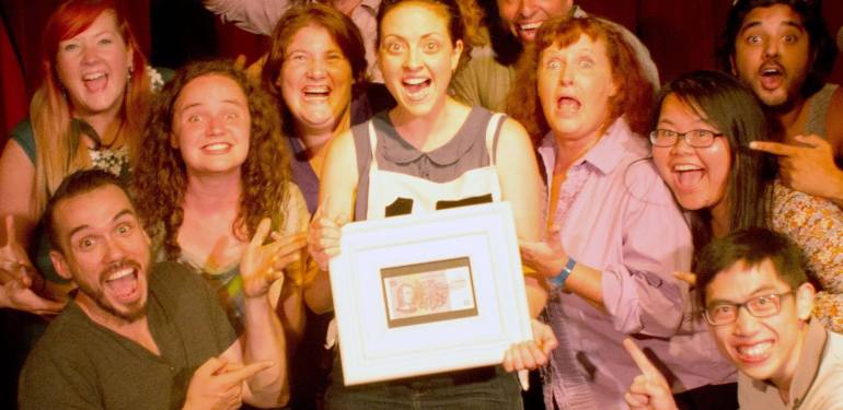 The cast of Maestro smile, holding a framed $5 note